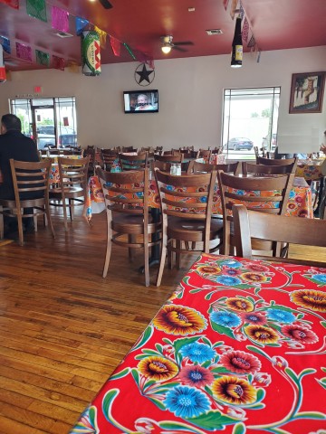 Inside of Caista Tejas Mexican Restaurant showing a warm interior with wood floors, wooden chairs and colorful decor.