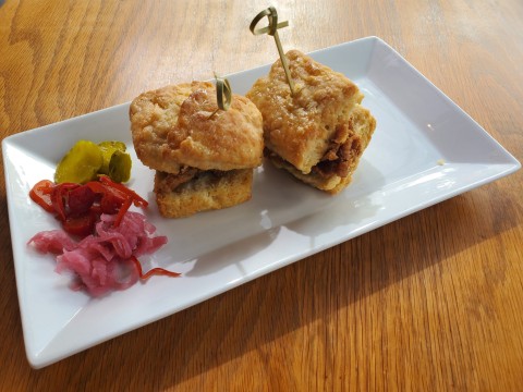 Root and Bone Chicken Biscuits at South Miami, created with chicken jus and benne seeds and honey butter. Served with homemade pickles and tobasco pepper jelly.