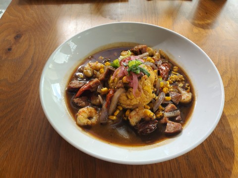 Shrimp and Grits with roasted tomatoes, onions, sweet corn, andouille sausage and royal red shrimp at the Root and Bone in South Miami